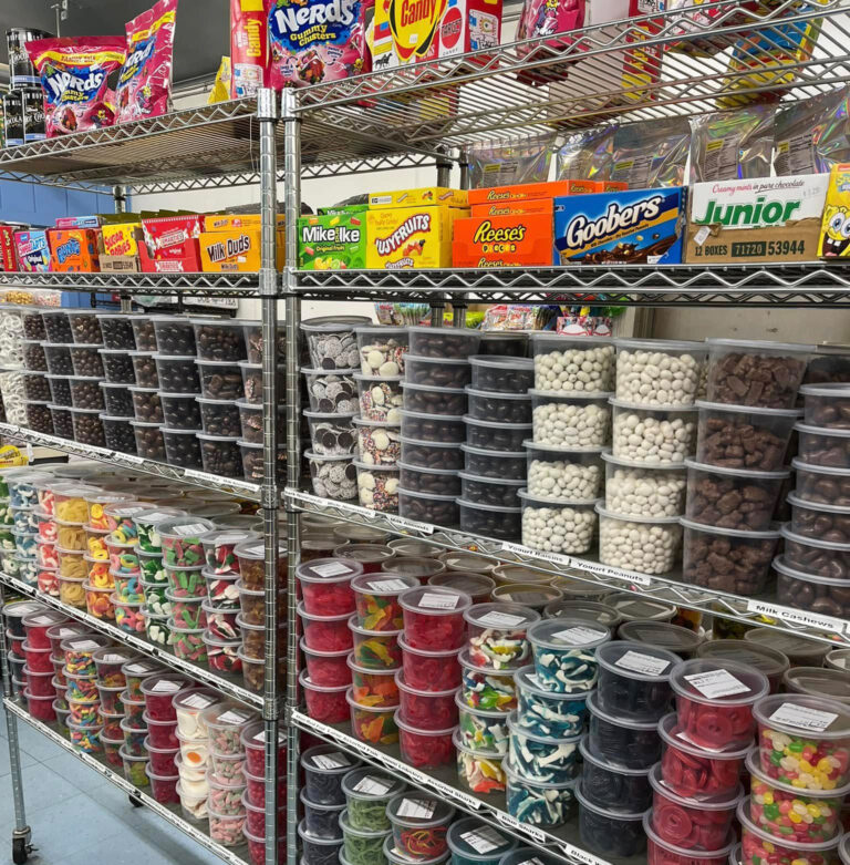A store shelf filled with clear containers of chocolates, gummies, and other candies.